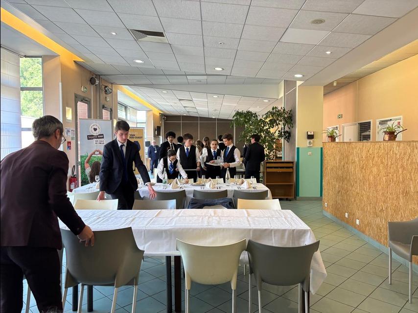 Étudiants de l'École de Cuisine de Toulouse en tenue de service, préparant les tables pour le déjeuner des jurés