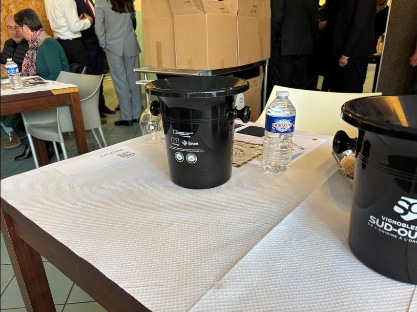 Crachoir noir posé sur la table de dégustation, feuille de notation et eau minérale en arrière-plan